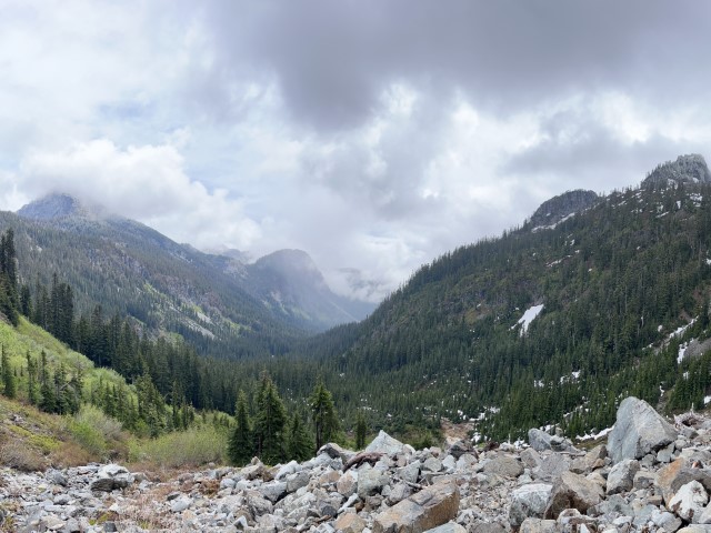 Low clouds cover forested valley with hints of late spring snow. Snowqualmie Pass, WA